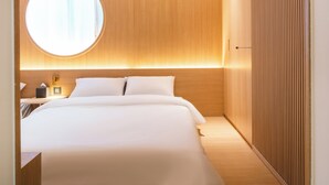 Una habitación de hotel moderna con una cama grande, un ventanal redondo y un panel de pared de madera.