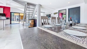 A spacious living area with a modern kitchen, a dining area with a large table set for six, and a staircase leading to an upper level. - Villa les Verdiers by Interhome (Biscarrosse)