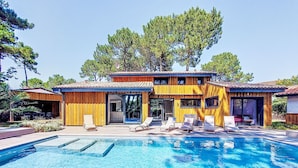 A modern wooden house with a swimming pool, lounge chairs, and a covered patio area. - Villa les Verdiers by Interhome (Biscarrosse)