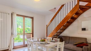 Un coin repas avec une table dressée pour quatre personnes, un escalier en bois et un canapé.