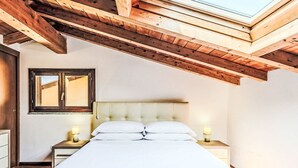Une chambre avec un puits de lumière, un lit, deux tables de chevet et une fenêtre.