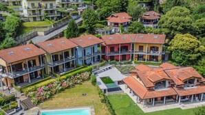 An aerial view of a residential complex with multiple buildings, a swimming pool, and well-maintained gardens. - Borgo Castello by Interhome (Argegno)