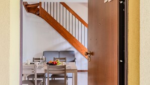 A dining area with a wooden staircase, a table set with chairs, and a door labeled B2. - Borgo Castello by Interhome (Argegno)