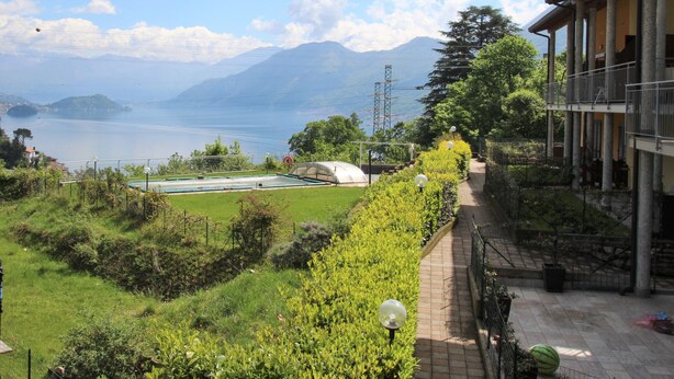Un hotel con vistas a un lago y montañas. Cuenta con piscina y un jardín con un sendero.