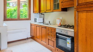 Una cocina con armarios de madera, un microondas, un hervidor y una estufa.
