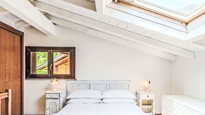Un dormitorio con tragaluz, cama, mesitas de noche y armario.