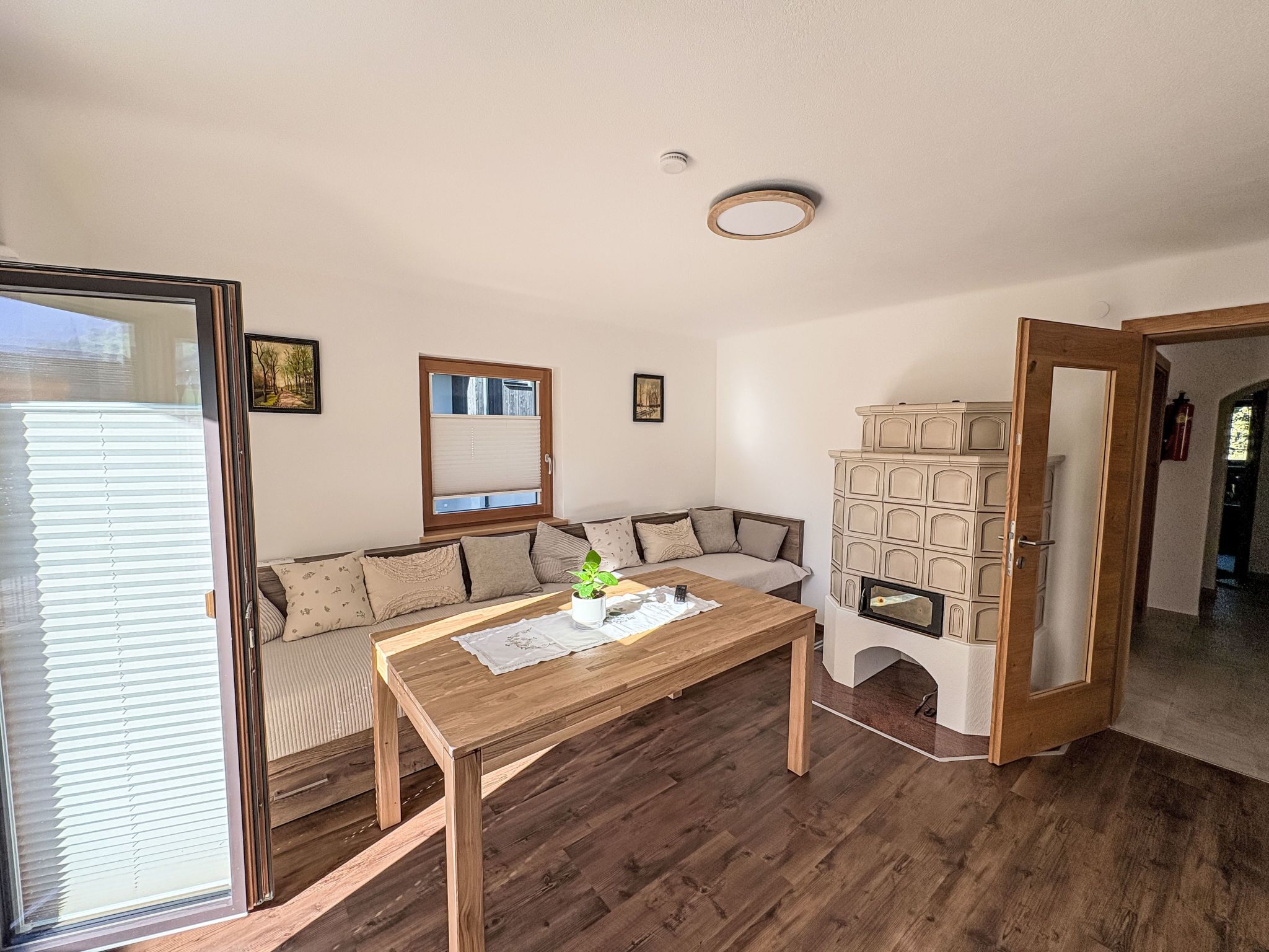 A cozy living room with a wooden table, a sofa, a built-in cabinet, and a sliding glass door.