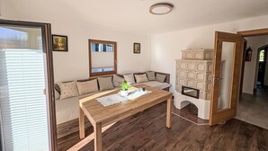 Een gezellige woonkamer met een houten tafel, een bank, een inbouwkast en een schuifdeur van glas.