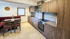 Een moderne keuken met houten kasten, een inbouwoven en een eethoek met een tafel en stoelen.