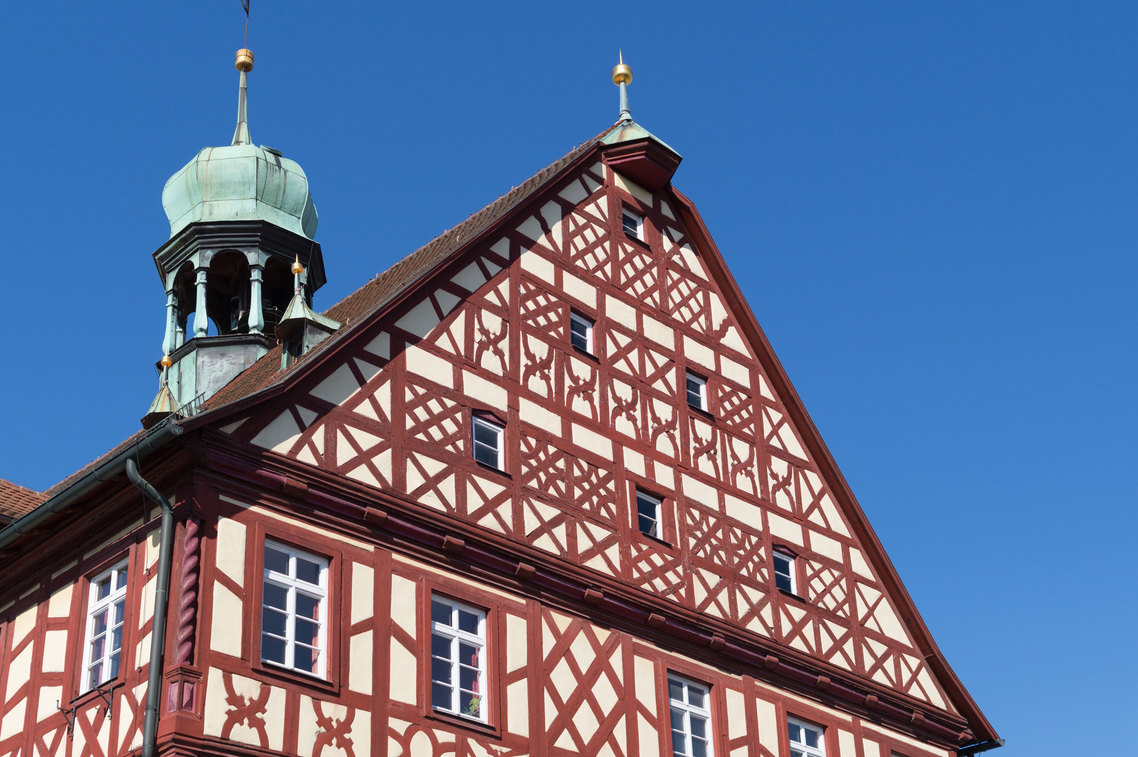 Un bâtiment traditionnel à colombages, doté d’une tour imposante, avec un ciel bleu clair en arrière-plan.