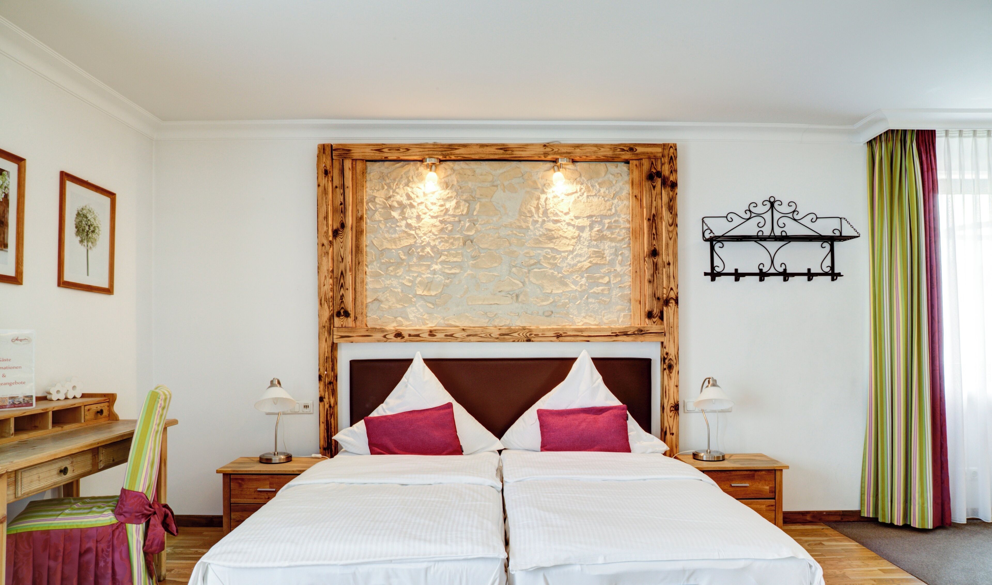 A double bed with a wooden headboard, two bedside tables with lamps, a wall-mounted shelf, and a striped curtain.
