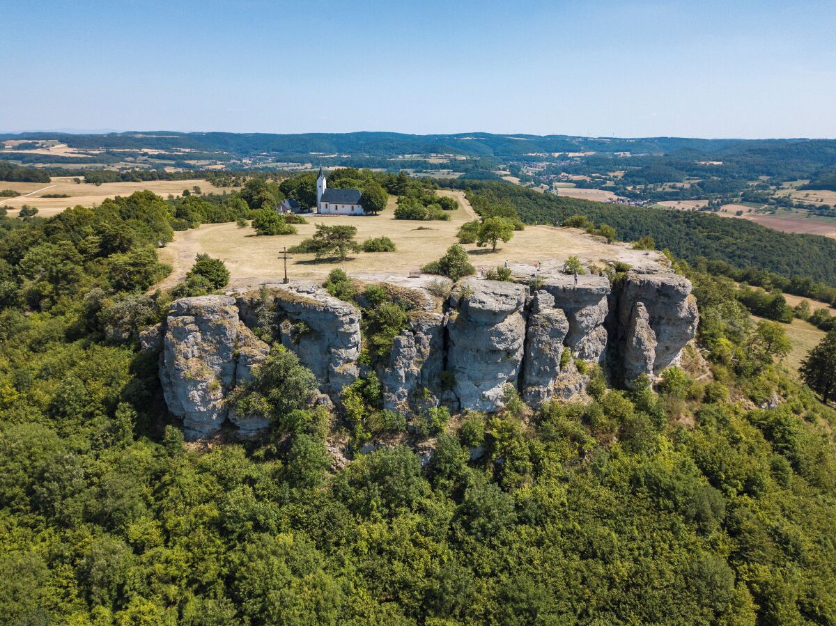 A church surrounded by rocky terrain and dense forest.