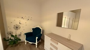 A room with a blue armchair, a white dresser, a mirror, and a wall decorated with dandelions and butterflies. - To feeling at home "at ANGELA's" (Montelabbate)