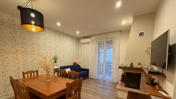 A dining area with a wooden table and chairs, a blue sofa, and a fireplace. - To feeling at home "at ANGELA's" (Montelabbate)
