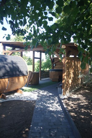 A covered outdoor area with a barbecue grill, wooden benches, and a wooden structure with a sloped roof.