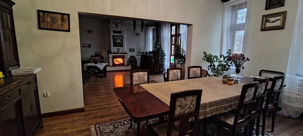 Un comedor con mesa y sillas de madera, chimenea y vista a otra habitación.