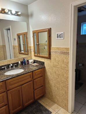 A bathroom with two sinks, a mirror, and a vanity with drawers.
