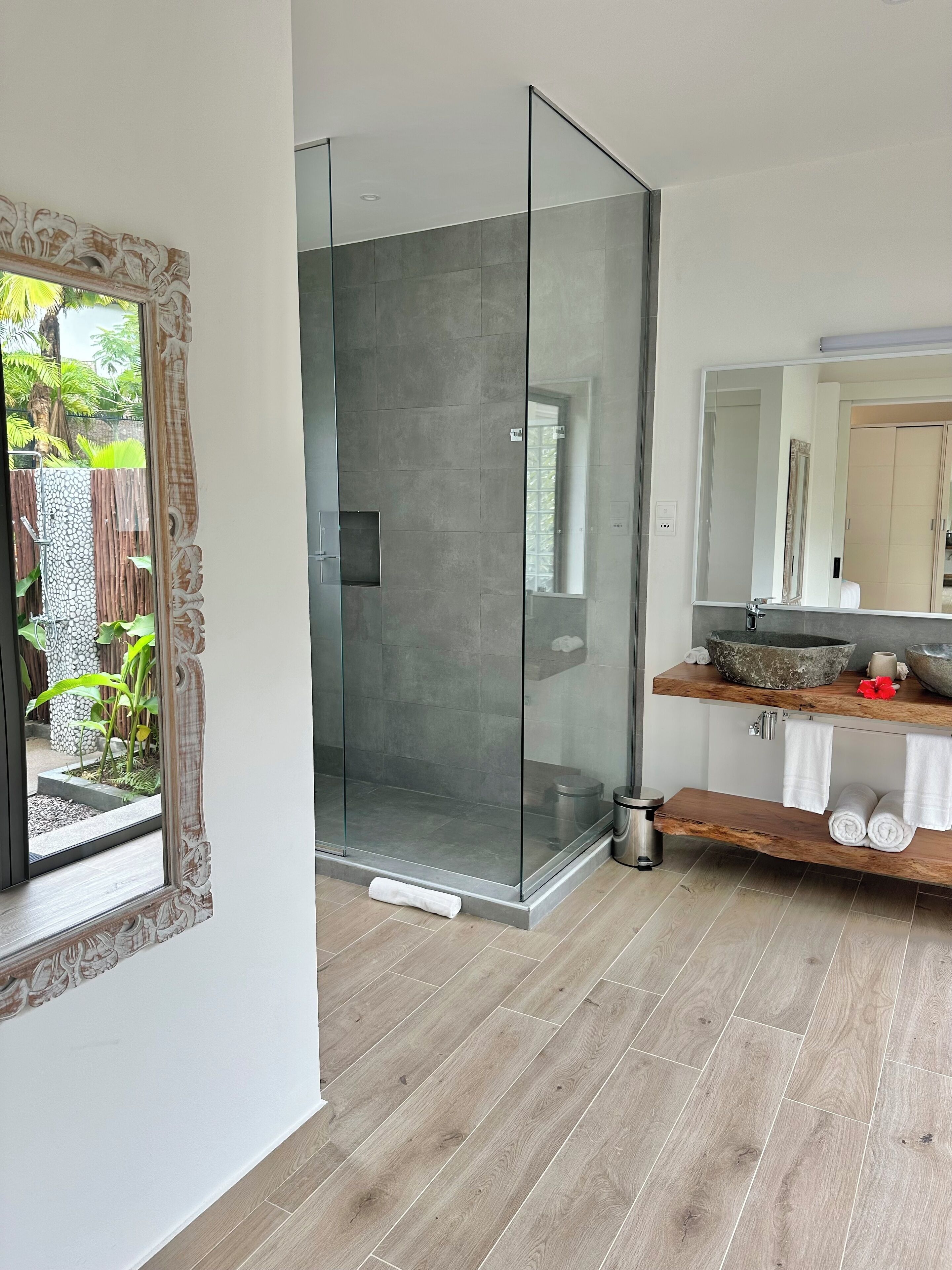 Une salle de bain moderne avec une douche à parois de verre, un meuble-lavabo en bois et un grand miroir.