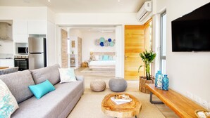 Een moderne woonkamer met een grijze bank, een houten salontafel en een televisie aan de muur.