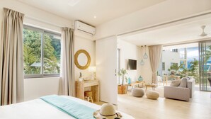 Een moderne hotelkamer met een groot bed, een bureau, een zithoek en een balkon met uitzicht op zee.