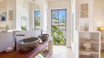Un baño moderno con un espejo grande, dos lavamanos de piedra y un mueble de tocador de madera.