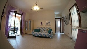 A living room with a sofa, a cabinet, and a ceiling light. - Villino Claudia (San Teodoro)