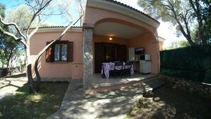 A house with a covered patio, a dining table with chairs, and a television. - Villino Claudia (San Teodoro)