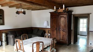Un'area pranzo con tavolo apparecchiato per quattro, circondato da sedie in legno, un mobiletto in legno scuro e un'ampia finestra.