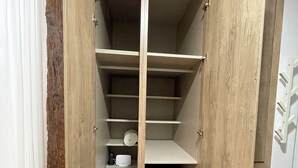A walk-in closet with wooden doors, multiple shelves, and a white storage unit. - WAKAFLATS 2 CHUECA SB (Madrid)
