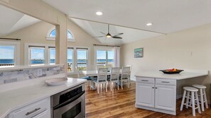 A spacious kitchen with a large island, white cabinetry, and a view of the ocean through large windows.