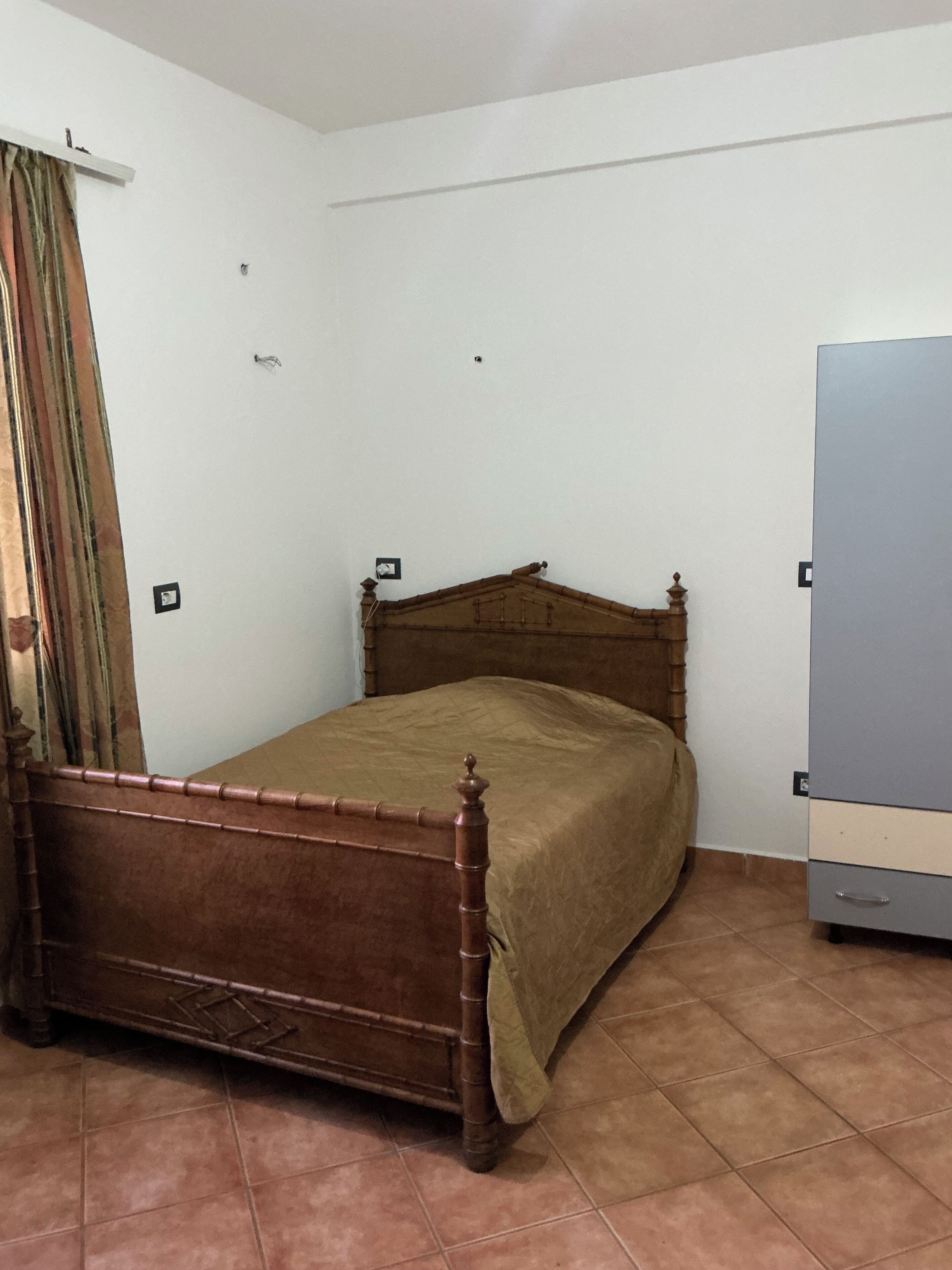 Une chambre à coucher avec un lit en bois, une armoire et un rideau.