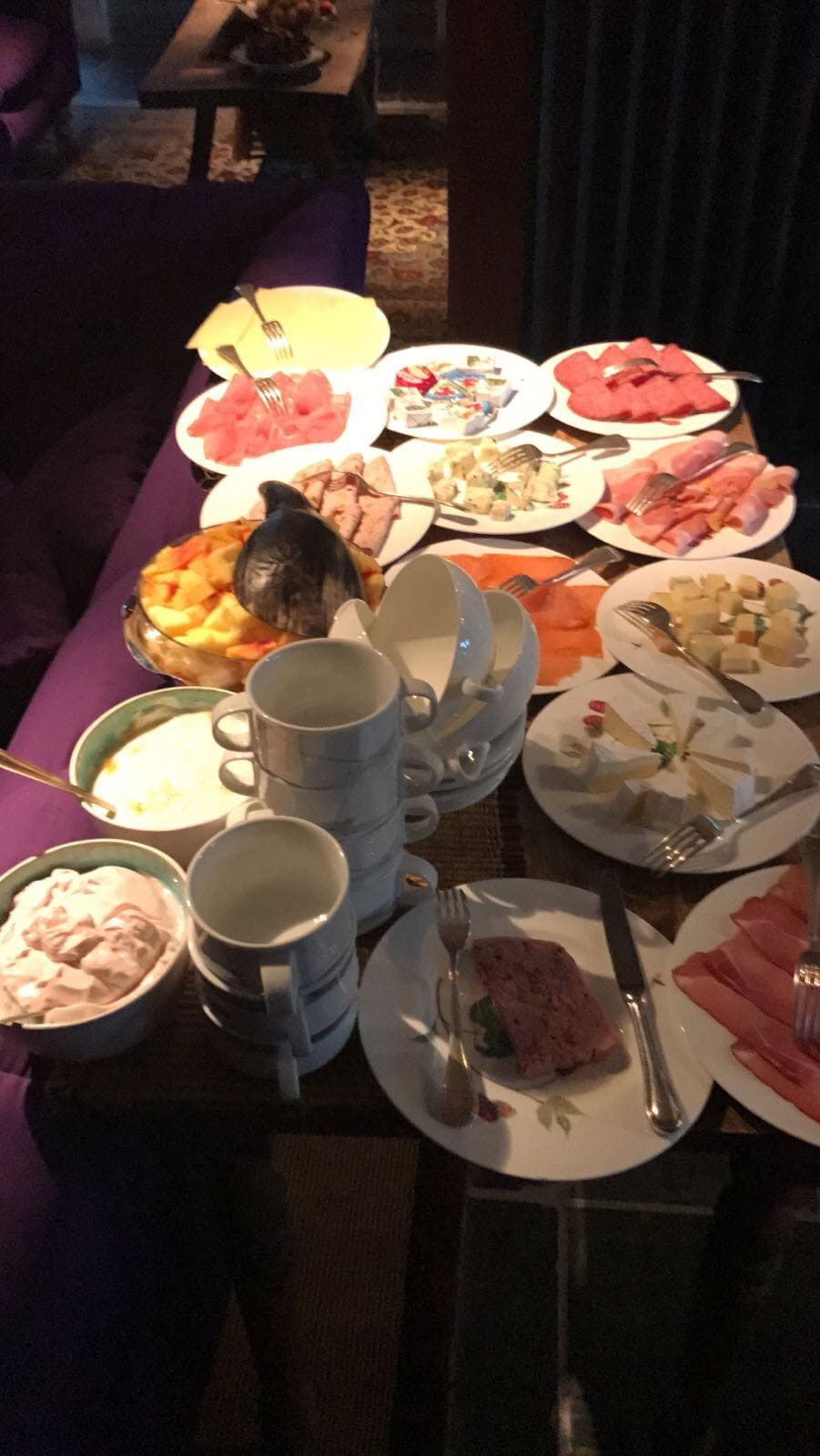 A dining table with various dishes, including a bowl of soup, a plate of meat, and several cups.