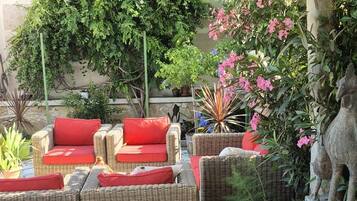 A covered outdoor seating area with wicker furniture and a stone floor.