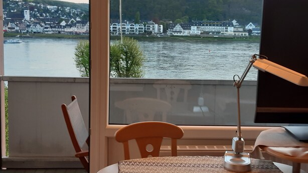 Una habitación con vista al río, una mesa con una lámpara y una silla.