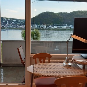 A room with a view of a river, a table with a lamp, and a chair. - Apartment with a view of the Rhine (Bad Hönningen)