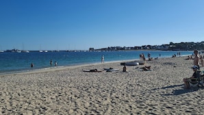 Una playa con barcos en el agua y gente en la arena.