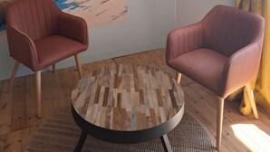Una habitación con dos sillones, una mesa redonda de madera y un mural con motivos playeros en la pared.