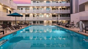 A hotel with a swimming pool, multiple balconies, and a modern architectural design.