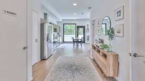 A modern kitchen with stainless steel appliances, a dining area with a large window, and a hallway leading to a door labeled "LAUNDRY".