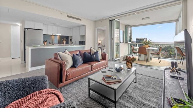 A modern apartment with a living area, kitchen, and balcony with a city view. - Top Floor! 2Bed/2Bath/1Car/Pool/Views ~ CBD (Brisbane City)