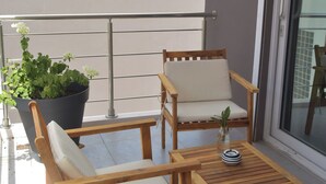 A balcony with two wooden chairs, a small table, and a potted plant.