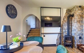 Un salon avec une horloge, une cheminée, un escalier et un luminaire moderne.