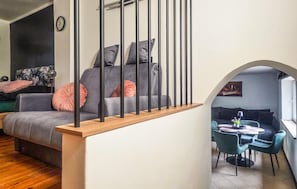Un espace de vie moderne comprenant un escalier, un canapé gris, des fauteuils turquoise et un coin repas.