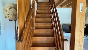 A wooden staircase with a handrail, leading to an upper floor.