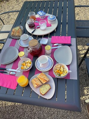 Ein Picknicktisch mit Tellern, Schüsseln, einem Teekännchen und einer Kanne.