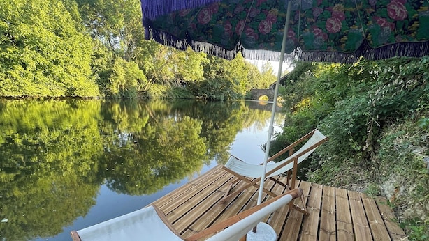 A wooden deck with a white lounge chair and a purple umbrella.