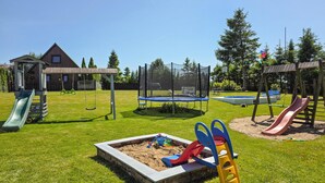 Un parque infantil con toboganes, columpios y un trampolín.