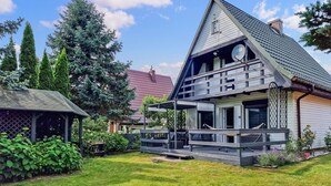 A two-story house with a sloped roof, a balcony, and a satellite dish.