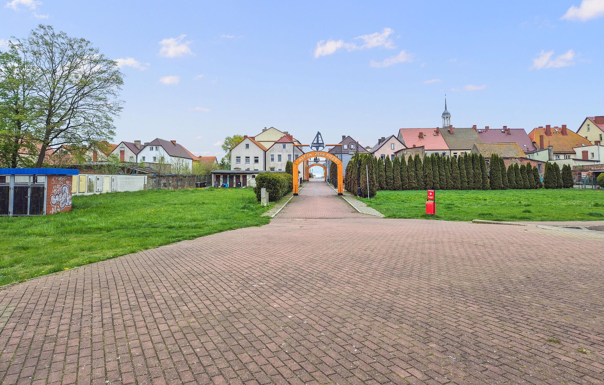 Un camino pavimentado que conduce a una zona residencial con casas y una iglesia.