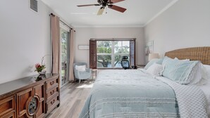 A bedroom with a bed, a dresser, a chair, a window, and a ceiling fan.